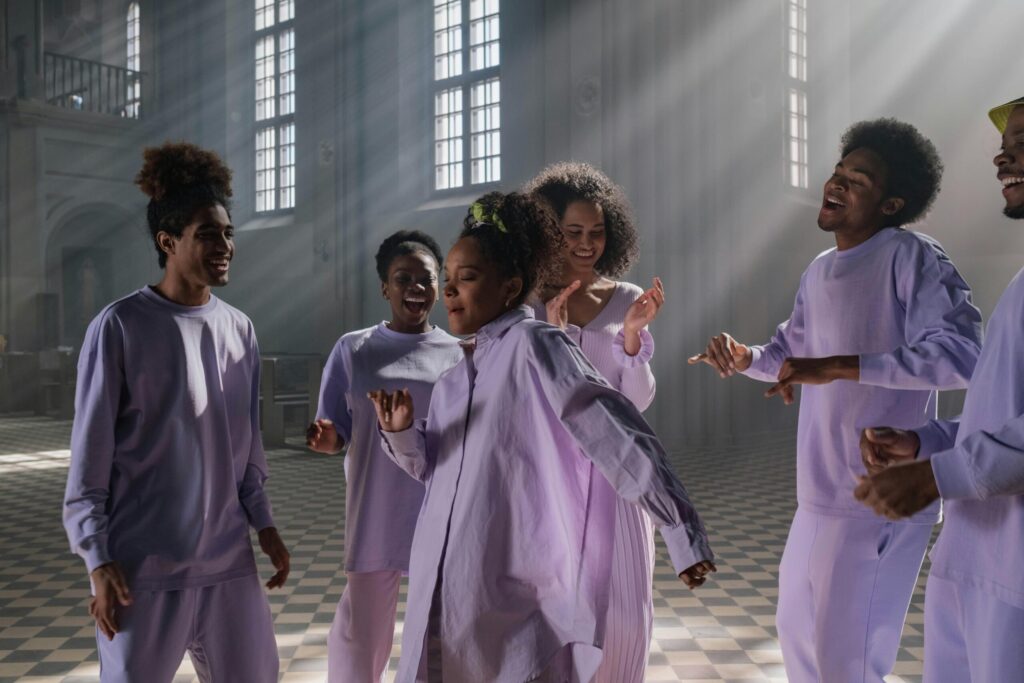Group of diverse singers practicing joyfully inside a sunlit church setting.